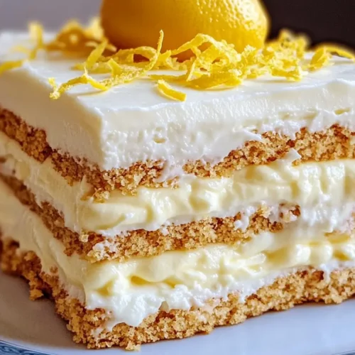 Lemon Icebox Cake with layers of graham crackers, lemon filling, and whipped cream topped with fresh lemon zest and a whole lemon.