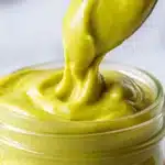 Close-up of creamy homemade pistachio cream recipe being spooned from a glass jar